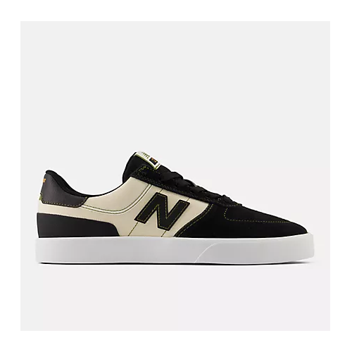 A New Balance low-top sneaker in black and cream suede, featuring a prominent black 'N' logo on the side, black laces, and a thick white platform sole, shown against a light gray background.