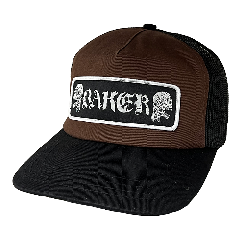 A brown and black trucker hat with a rectangular front patch featuring the word 'BAKER' in white gothic lettering between two skull illustrations, shown on a plain white background.