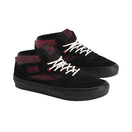 A pair of black mid-top skate shoes with red graphic patterns and white laces, displayed on a light beige background.