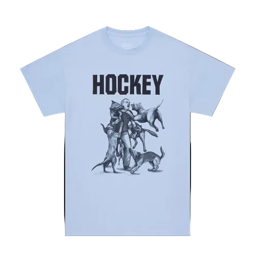 A light blue short-sleeve t-shirt with a graphic print featuring the word 'HOCKEY' in bold black letters above a black and gray sketch of a hockey player surrounded by dogs, shown against a white background.