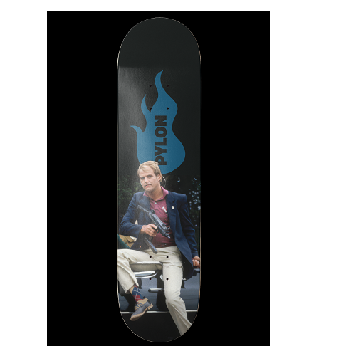 A skateboard deck featuring a graphic print of a man in a blue blazer and beige pants sitting on a bench holding a weapon, with a large blue flame logo and the word 'PYLON' on a black background.