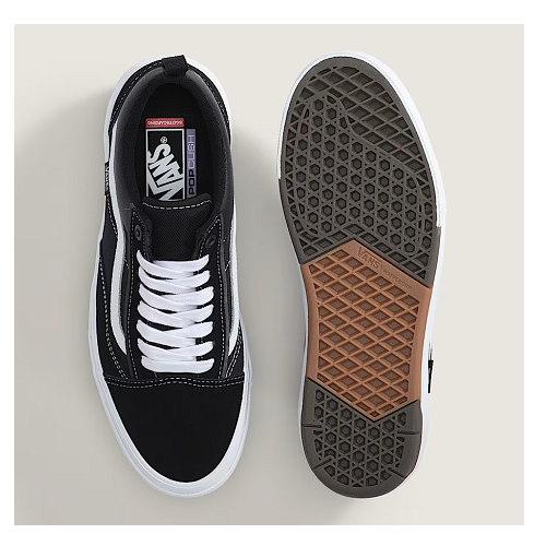 A pair of Vans Old Skool sneakers shown from the top and bottom views on a light beige background. The top view shows a black suede and canvas upper with white laces and a white rubber sole. Bottom view shows gum sole. 